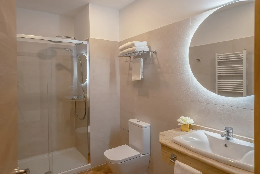 Cuarto de baño completo con toallas, secador y luz natural